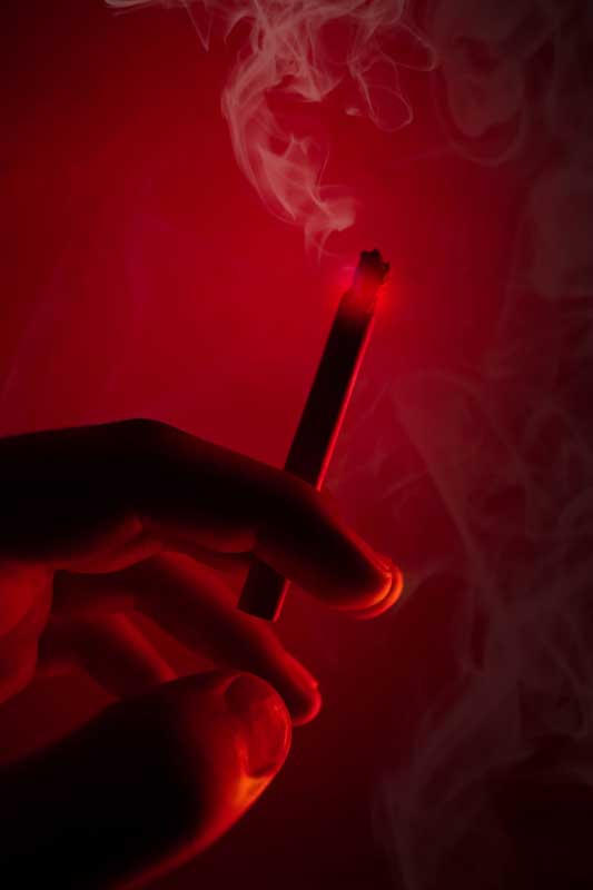 تصویر گرافیکی سیگار در دست زیر نور قرمز
