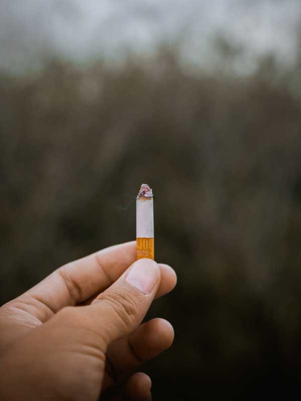تصویر گرافیکی یک نخ سیگار روشن در دست